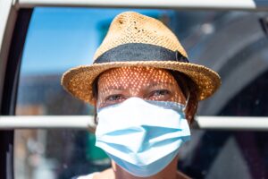 woman in brown hat with white face mask